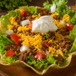 beef taco salad topped with chedder and sour cream