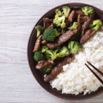 beef with broccoli and rice on a plate on the table. horizontal view from above
